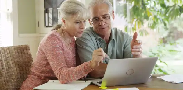 Idős házaspár együtt használja a laptopot az otthonában